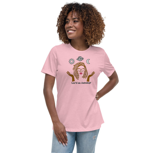 A person wearing a pink tee with an illustration of a person with locs, surrounded by astrological symbols, and the text "Loc'd on Astrology."